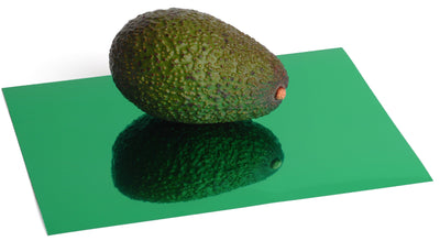 Green foil board with a reflective, mirrored finish. An avocado sits atop the foil board and is reflected in its surface.