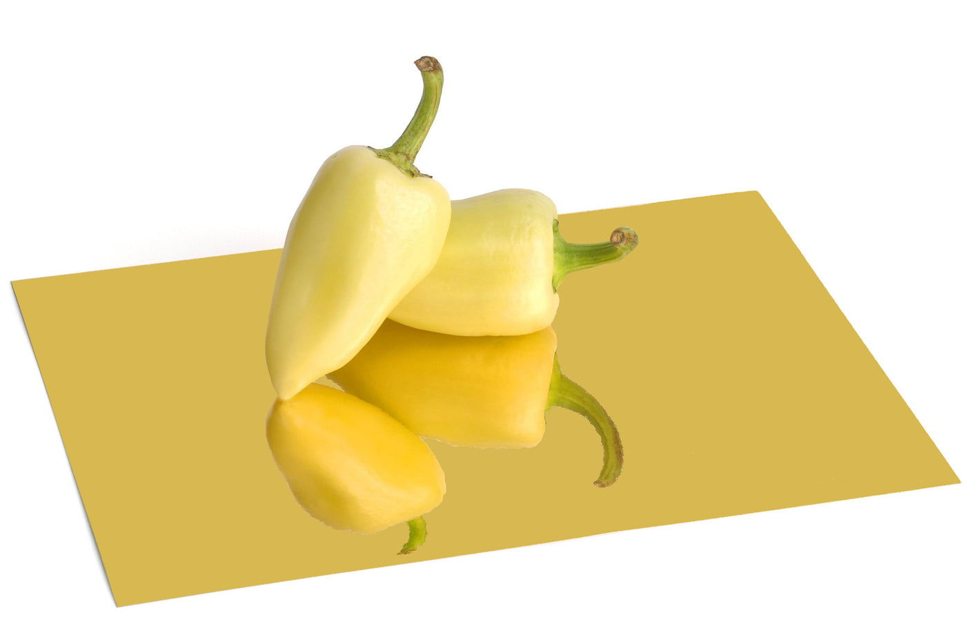 Gold foil board with a reflective, mirrored finish. Two peppers sit atop the foil board and are reflected in its surface.